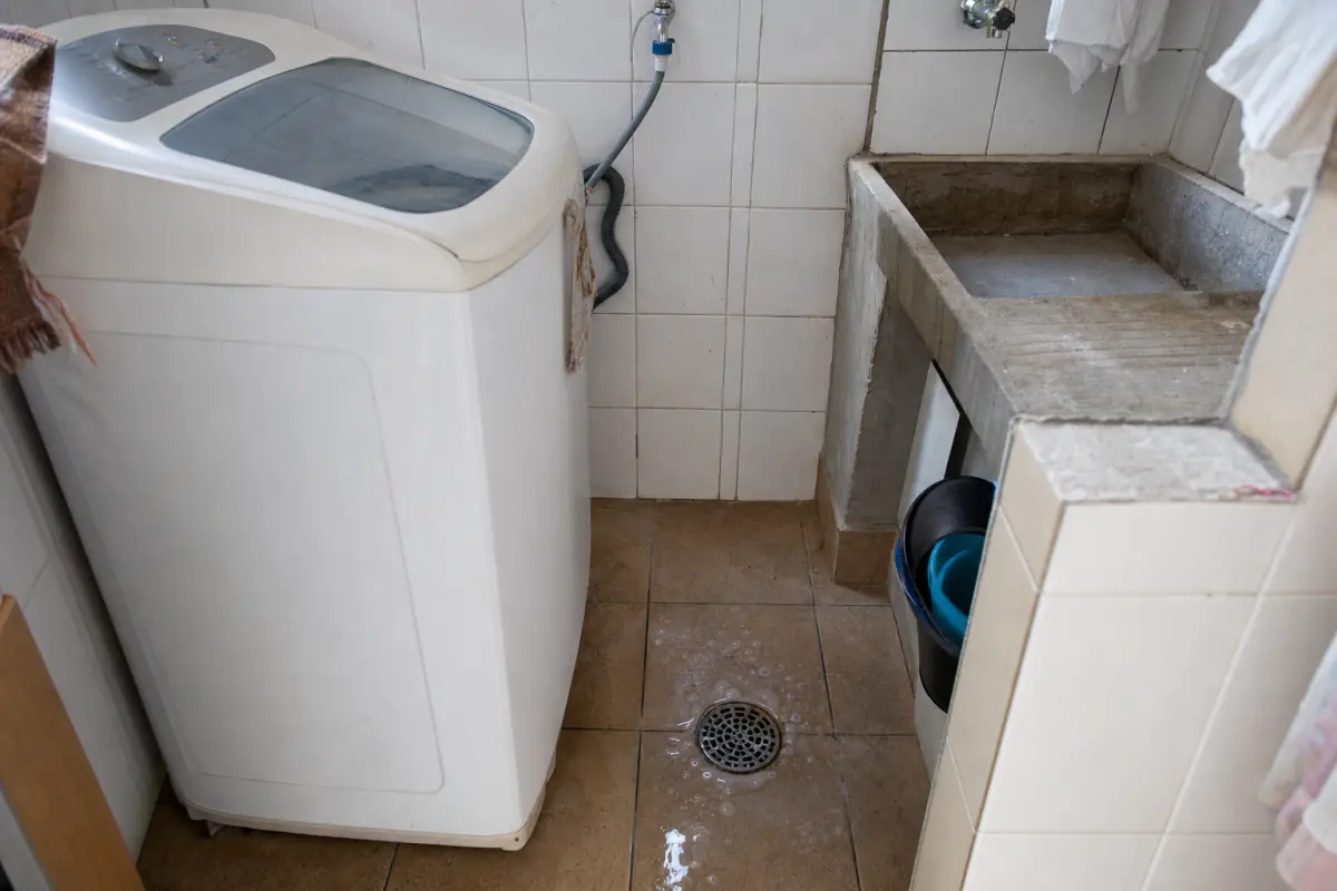 Ralo de piso de uma lavanderia com água e espuma de sabão empoçadas em volta da grelha