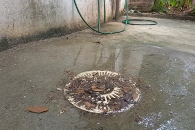 Como desentupir ralo: ralo de quintal coberto de folhas e terra com água suja parada em volta da grelha